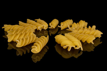 Lot of whole yellow pasta fusilli circle isolated on black glass