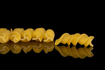 Lot of whole yellow pasta fusilli pieces isolated on black glass