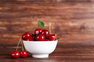 Sweet cherries in bowl on brown wooden table - Powered by Adobe