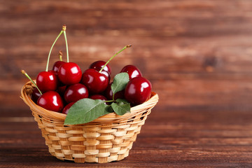 Fototapeta na wymiar Sweet cherries in basket on brown wooden table