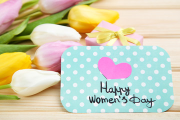 Text Happy Womens Day with tulip flowers on brown wooden table