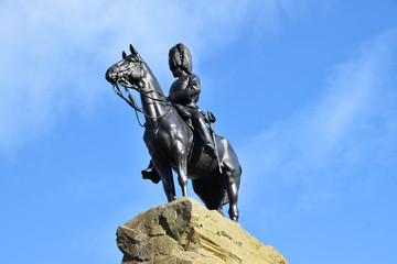 Fototapeta na wymiar Statue memorialising the Royal Scots Greys and their fight in World War One. Statue is of solider on horseback on top of a rock. Isolated with blue sky background. Edinburgh, Scotland, UK.