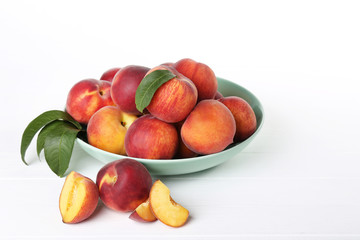 Fresh peaches in plate on white wooden table