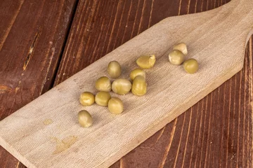 Foto op Plexiglas Lot of whole canned pea on wooden cutting board on brown wood © PIXbank
