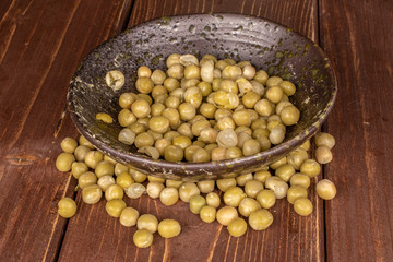Lot of whole canned pea in glazed bowl on brown wood