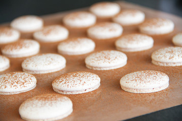 French dessert macaron. The photo of making macaron powdered with cocoa powder. Macaron in process,...
