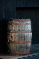old wooden barrel with rusty hoops against a dark wall