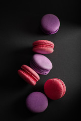 Multi-colored macaroons scattered on a dark background. International Women's Day. French national cuisine.