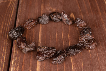 Lot of whole dried dark raisin circle on brown wood