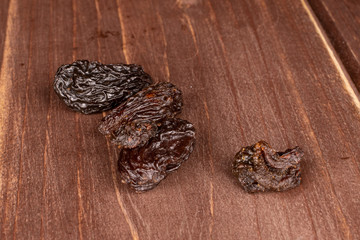 Lot of whole sweet dried dark raisin on brown wood