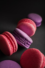 Pink and purple macaroons on a dark background. International Women's Day. French national cuisine. Food shot.