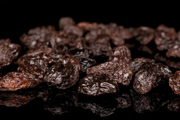 Lot of whole dried dark raisin front focus isolated on black glass