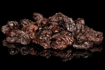 Lot of whole dried dark raisin heap isolated on black glass