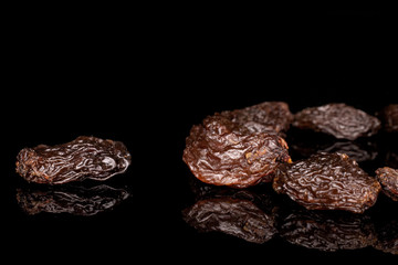 Lot of whole sweet dried dark raisin isolated on black glass