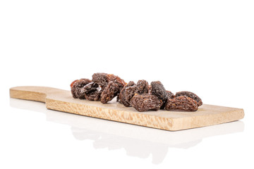 Lot of whole dried dark raisin on wooden cutting board isolated on white background