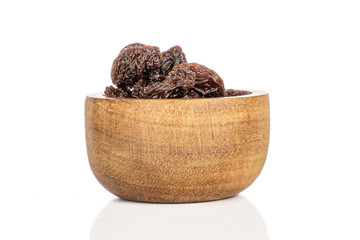 Lot of whole dried dark raisin in bamboo bowl isolated on white background