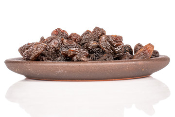 Lot of whole dried dark raisin with brown ceramic coaster isolated on white background