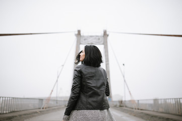 Back view. Beautiful girl walking on the bridge enjoing her life, urban lifestyle. Soft focus.
