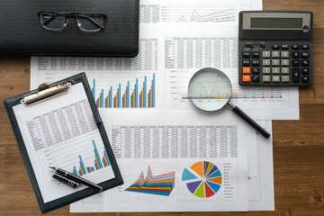 Financial documents - graphics, statistics, drawings, keyboard, laptop, magnifying glass in the...