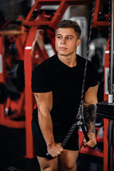 Young man doing cable tricep pulldowns during a gym workout
