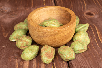 Lot of whole wasabi green peanut in bamboo bowl on brown wood