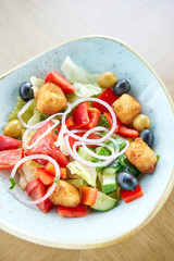 Traditional greek salad with fresh vegetables, feta cheese and olives. Wooden table in restaurant