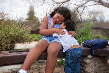 Siblings having fun playing together and the little brother is tickling the older sisters neck,...