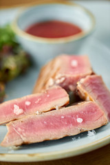 Closeup Medium rare tuna with lettuce and hot sauce. Restaurant menu