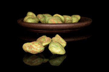 Lot of whole wasabi green peanut with brown ceramic coaster isolated on black glass