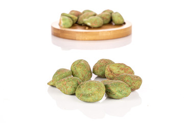 Lot of whole small wasabi green peanut on round bamboo coaster isolated on white background