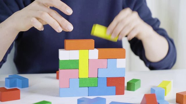 A girl is building a house from multi-colored blocks of cubes.