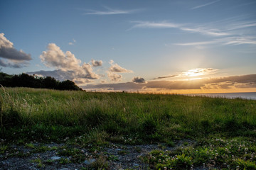 Golden sunse scene with green grass hills and ocean behind at Chiloe Island, Chile