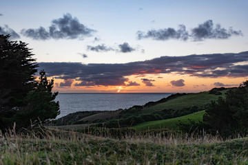 Obraz premium Golden sunset with green hills and blue ocean at Chiloe Island, Chile