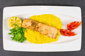 Beautiful grilled salmon with potato mash on white rectangular ceramic plate flatlay on grey stone