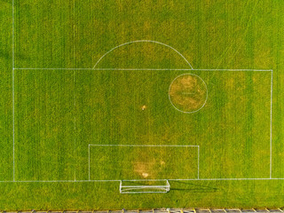 Aerial top down view on a green football pitch with trees shadows. Nobody. Sunny day.