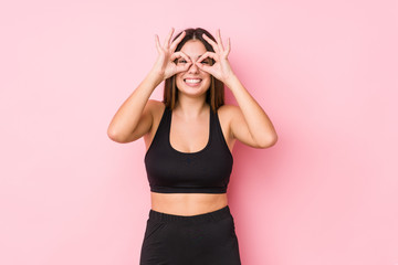 Young fitness caucasian woman isolated showing okay sign over eyes