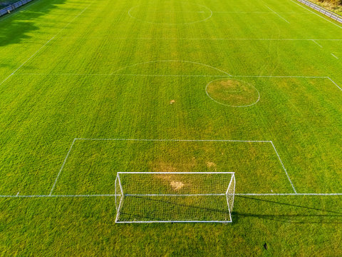 Aerial View On A Green Football Pitch With Trees Shadows. Nobody. Sunny Day.