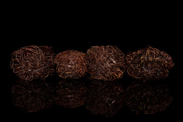 Group of four whole old brown rambutan isolated on black glass