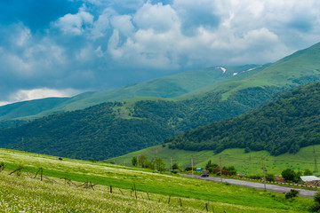 Fototapeta na wymiar Blue clouds push by green picturesque mountains of the Caucasus, landscape of Armenia
