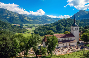 Gruyères, Canton of Fribourg / Switzerland - August 5th, 2008: The Saint Theodule Church and its cemetery as seen from the Chateau de Gruyères, with the Sarine/Saane Valley in the background