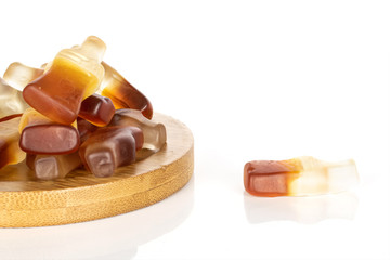 Lot of whole sweet sweet jelly cola on round bamboo coaster isolated on white background