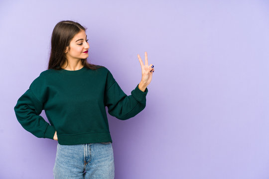 Young caucasian woman isolated on purple background joyful and carefree showing a peace symbol with fingers.