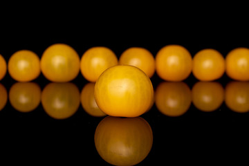 Group of nine whole fresh yellow tomato isolated on black glass