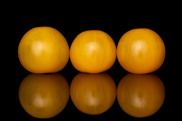 Group of three whole fresh yellow tomato isolated on black glass