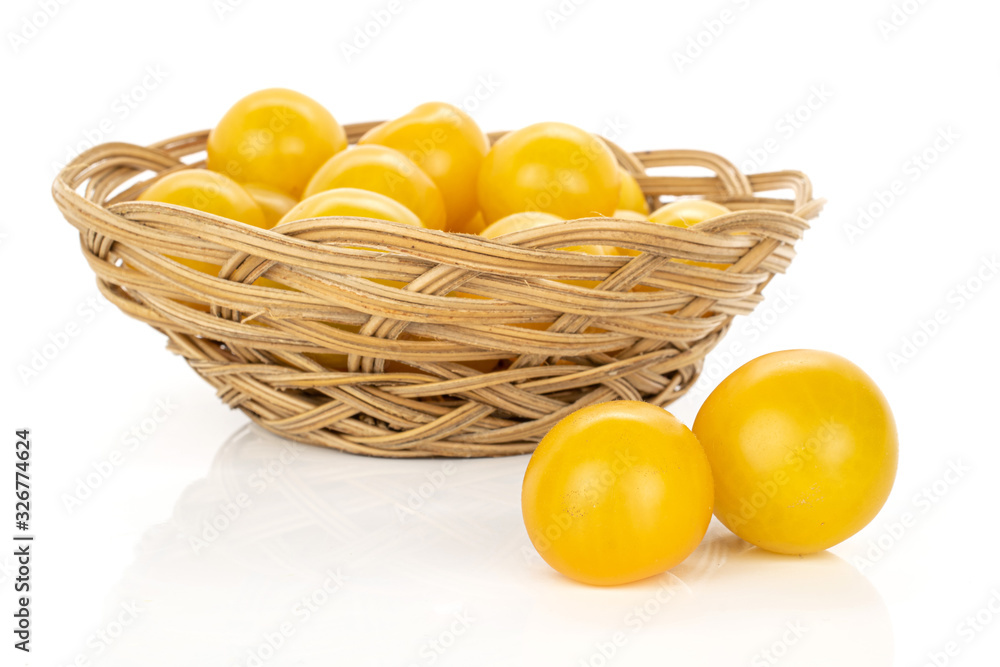 Wall mural Lot of whole fresh yellow tomato in round rattan bowl isolated on white background