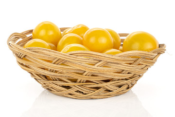 Lot of whole fresh yellow tomato in round rattan bowl isolated on white background