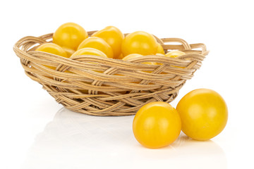 Lot of whole fresh yellow tomato in round rattan bowl isolated on white background