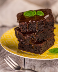 A stack of chocolate brownies on wooden background with mint leaf on top, homemade bakery and dessert
