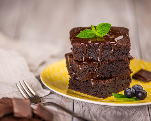 A stack of chocolate brownies on wooden background with mint leaf on top, homemade bakery and dessert