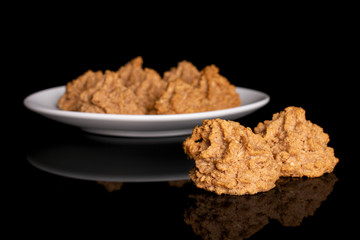 Group of nine whole homemade brown coconut biscuit with chocolate on white ceramic plate isolated on black glass